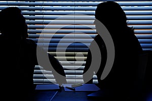 Silhouette of male and female coworkers flirting in office