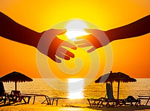 silhouette of male and female hands on the background of a sea sunset. concept of communication and striving for closeness in
