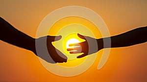 Silhouette of male and female hands on the background of the setting sun. concept of communication and striving for closeness in