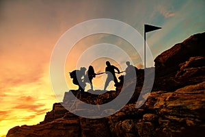 Silhouette male and female hikers climbing up mountain cliff, Helps and team work concept.