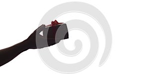 Silhouette of male hands giving a gift box with bow for his beloved on white isolated background, concept holidays, care, surprise