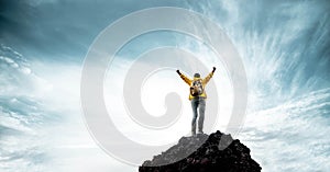 Silhouette of male on the mountain with open arms - Successful hiker exult on the top of the rock photo