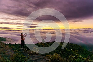 Silhouette of male photographer or traveler taking a photograph sunrise landscape on mountain top at Doi Inthanon National Park