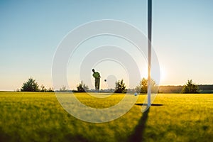 Silhouette of a male player hitting a long shot on the putting g