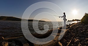 Silhouette of man angling on the river shore