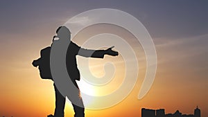 Silhouette of a man with a backpack against bright sky sunset