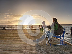 Silhouette of man with backpack on the pier on the calm sea