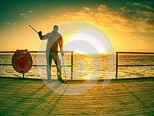 Silhouette of man with backpack on the pier on the calm sea