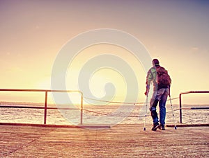 Silhouette of man with backpack on the pier on the calm sea