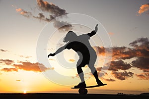 Silhouette of the man balancing on the balance board on the ocean shore