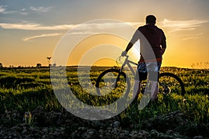 Silhouette of man with bicycle at sunset