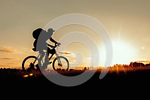 Silhouette of a man on a bicycle on a sunset background