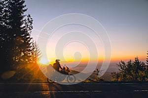 Silhouette of man biker and adventure motorcycle on the road with sunset light background. Top of mountains, tourism motorbike,