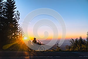 Silhouette of man biker and adventure motorcycle on the road with sunset light background. Top of mountains, tourism motorbike,