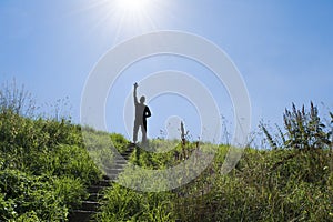 Silhouette of man in bright sunlight on top of a stairs