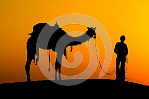 Silhouette of a man and camel at sunset in the desert, Jaisalmer - India