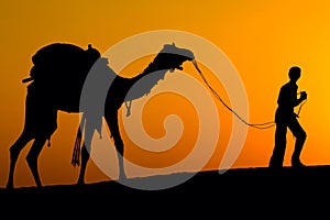 Silhouette of a man and camel at sunset in the desert, Jaisalmer - India