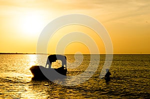 Silhouette of man carrying the anchor of boat out to sea