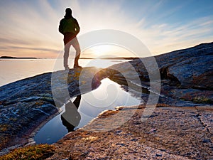 Silhouette man on cliff above sea. Tourist stand alone on rock and watch sea horizon