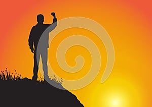 Silhouette of man on the cliff with fist raised up on golden sunrise background, successful, achievement and winning concept