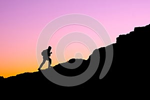 The silhouette of a man climbing a mountain in the sunset light