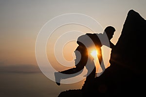 Silhouette of man climbing rock, Photographer on the mountain at sunrise