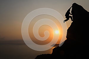 Silhouette of man climbing rock, Photographer on the mountain at sunrise