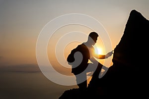 Silhouette of man climbing rock, Photographer on the mountain at sunrise