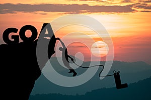 Silhouette Man climbs into cliff to make word GOAL (goal setting concept)