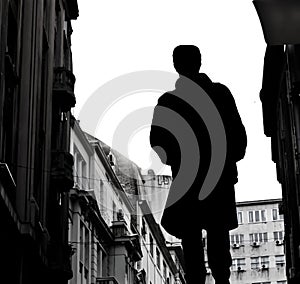 Silhouette of a man in coat and city buildings