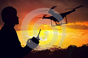 Silhouette of man controlling a drone at sunset
