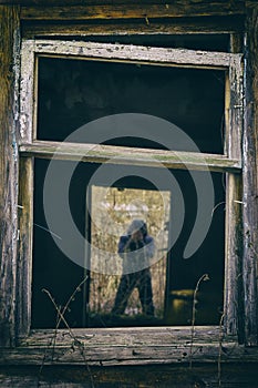 Silhouette of a man covering his face with hands in the doorway of abandoned house