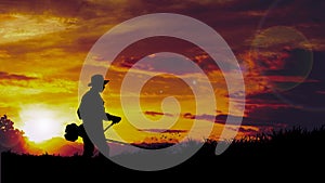 Silhouette of a man cutting grass mowing grass