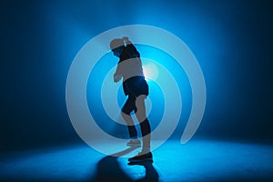 Silhouette of man dancing in club with blue neon lightning and smoke.