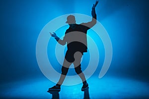 Silhouette of man dancing in club with blue neon lightning and smoke.