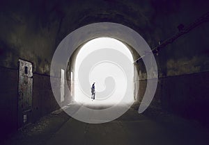 Silhouette of a man disappearing into the light at the end of a tunnel. photo