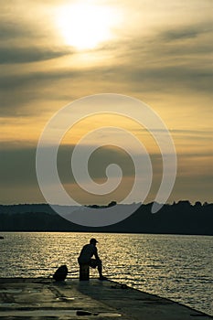 Silhouette of man on dock of shimmering lake