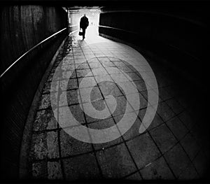 Silhouette of man entering a dark tunnel in black and white
