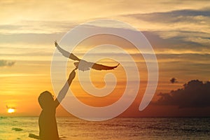 Silhouette of man feeding seagull at sunset