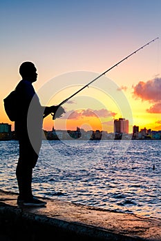 Silhouette of a man fishing on the bay of Havana at sunset