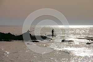 Silhouette of man fishing at the sea