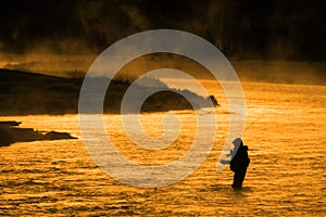 Silhouette of Man Flyfishing Fishing in River Golden Sunlight