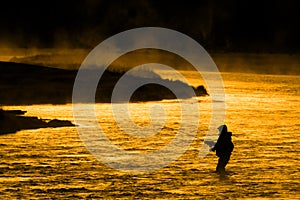 Silhouette of Man Flyfishing Fishing in River Golden Sunlight