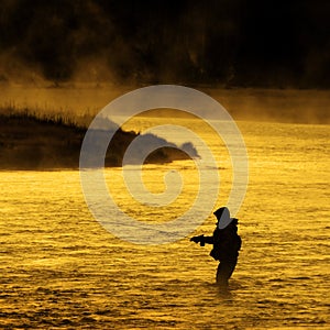 Silhouette of Man Flyfishing Fishing in River Golden Sunlight photo