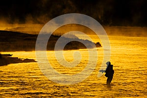 Silhouette of Man Flyfishing Fishing in River Golden Sunlight photo