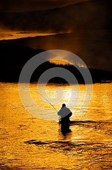 Silhouette of Man Flyfishing in River