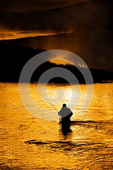 Silhouette of Man Flyfishing in River photo