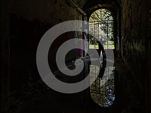 Silhouette of a man in front of a large arched door of an abandoned madhouse