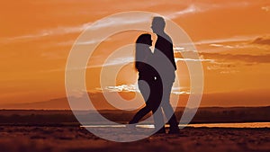 Silhouette man and girl of a happy young married couple slow dancing outside at sunset. Couple enjoying on nature the