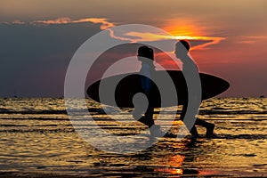 Silhouette Of man and girl surfers running to the sea with surf